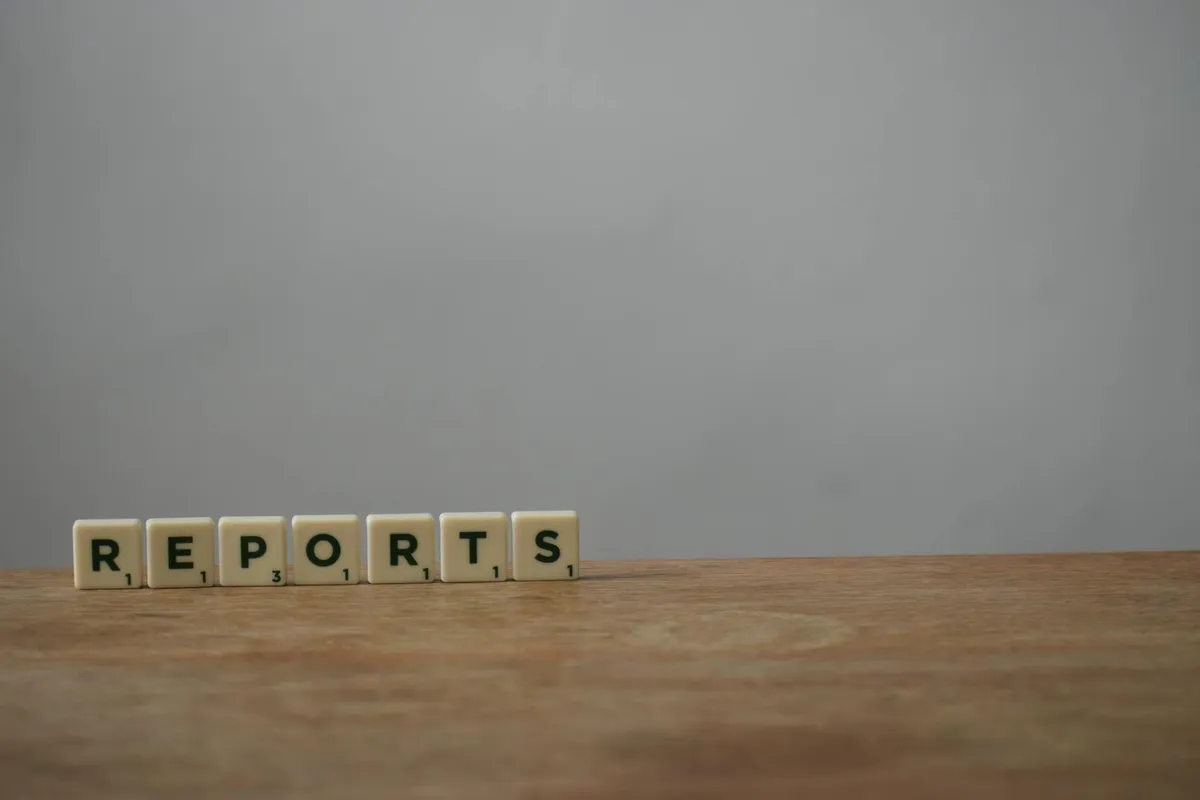 Scrabble tiles spelling 'reports' on a wooden desk, ideal for office or business themes.