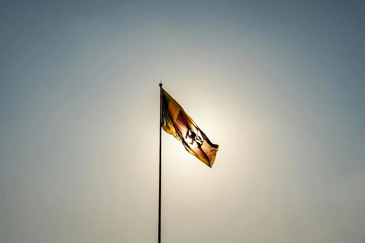 The Sri Lankan flag waves majestically in front of a bright sun in Colombo.